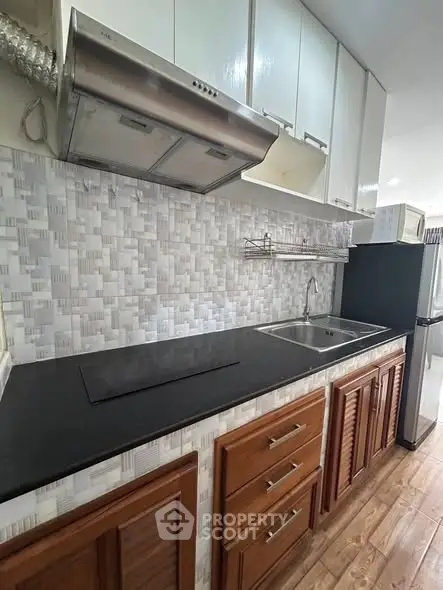 Modern kitchen with sleek cabinetry and stainless steel appliances in a stylish apartment.