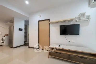 Modern living room with sleek TV setup and washing machine in open layout.