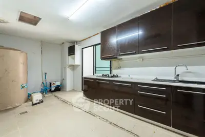 Spacious kitchen with dark cabinets and gas stove, ideal for modern cooking.