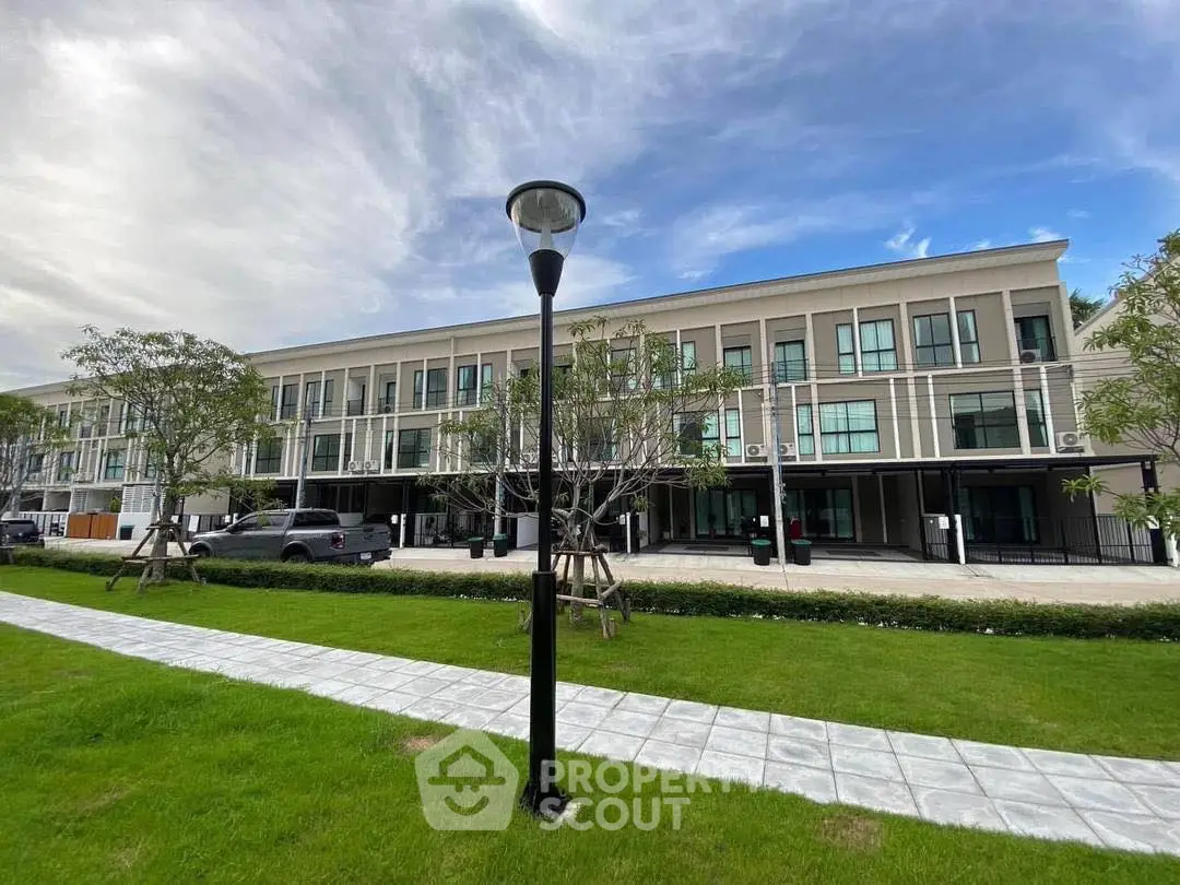 Modern townhouse complex with lush green lawn and clear blue sky