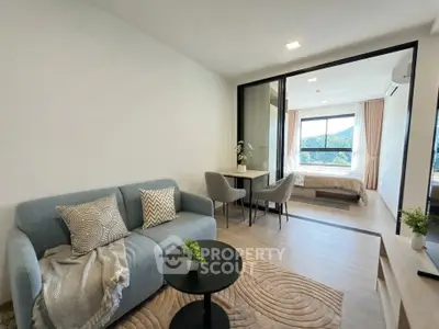 Modern open-plan living room with cozy seating and bedroom view, featuring stylish decor and natural light.