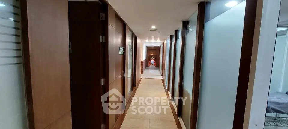 Modern corridor with wooden doors and frosted glass panels in a contemporary building.