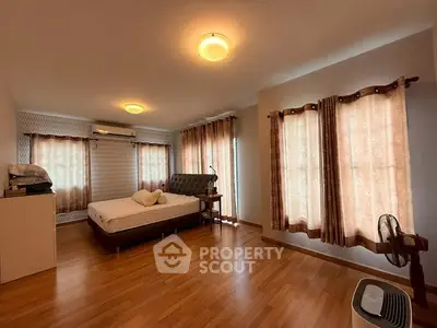 Spacious bedroom with wooden flooring and elegant curtains