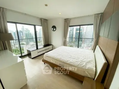 Spacious bedroom with large windows offering stunning city views in a modern apartment.
