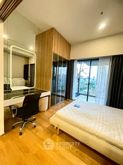 Modern bedroom with city view, featuring a stylish desk and large mirrored wardrobe.
