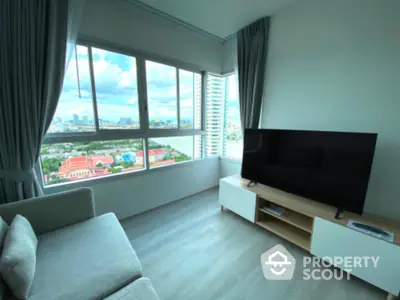 Modern living room with large windows and city view, featuring sleek furniture and natural light.