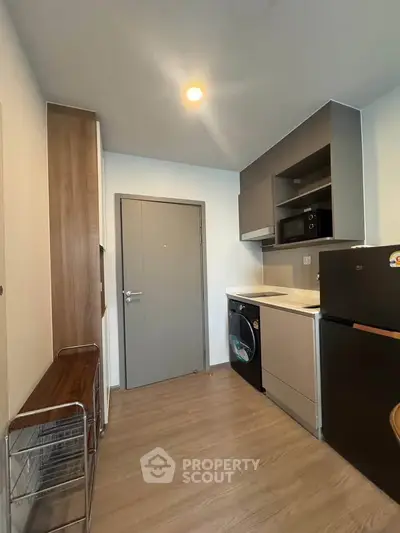 Modern kitchen with sleek appliances and wood flooring in a compact layout.