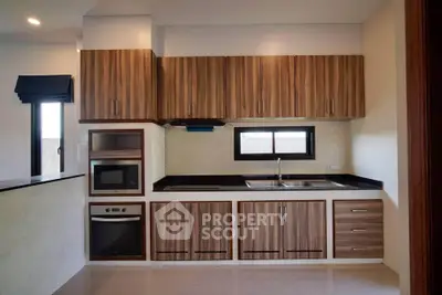 Modern kitchen with sleek wooden cabinets and built-in appliances, perfect for culinary enthusiasts.