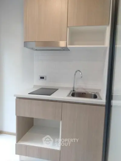 Modern compact kitchen with sleek cabinetry and electric cooktop
