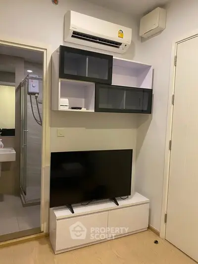 Modern living room with sleek TV unit and air conditioning, adjacent to a stylish bathroom.