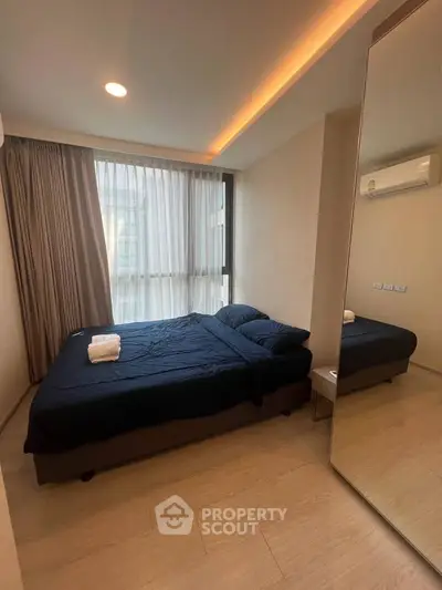 Modern bedroom with large window and elegant lighting in a stylish apartment.