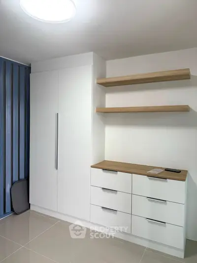 Modern minimalist storage room with sleek white cabinets and wooden shelves.