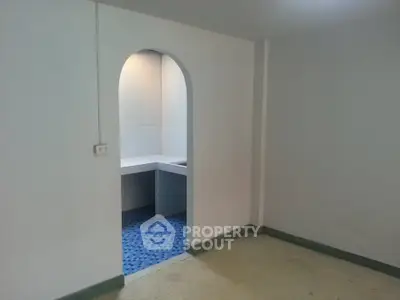 Minimalist interior with archway leading to tiled area, ideal for creative renovation.