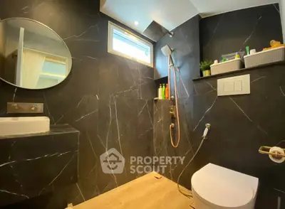 Luxurious modern bathroom with sleek black marble walls and elegant fixtures.