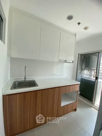 Modern kitchen with sleek cabinetry and balcony access in a bright apartment.
