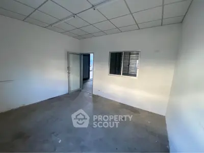 Spacious empty room with concrete floor and window, ideal for customization.