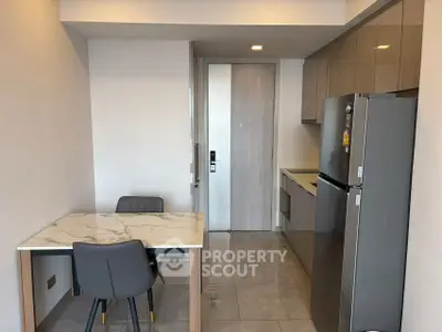 Modern kitchen with sleek cabinetry and dining area in contemporary apartment.
