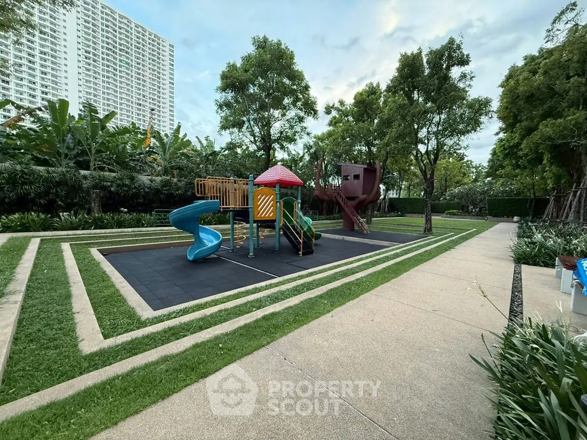 Spacious garden with modern playground in a residential complex, perfect for family living.