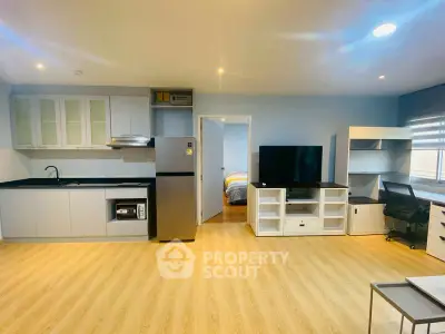 Modern open-plan living room with kitchen and study area, featuring sleek appliances and stylish decor.