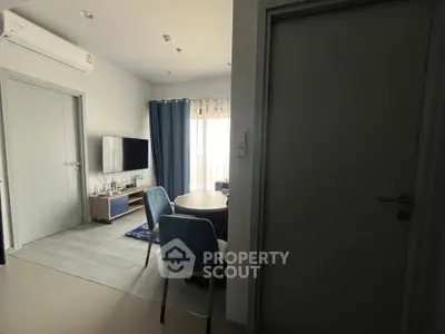 Modern living room with dining area and balcony access, featuring sleek furniture and natural light.