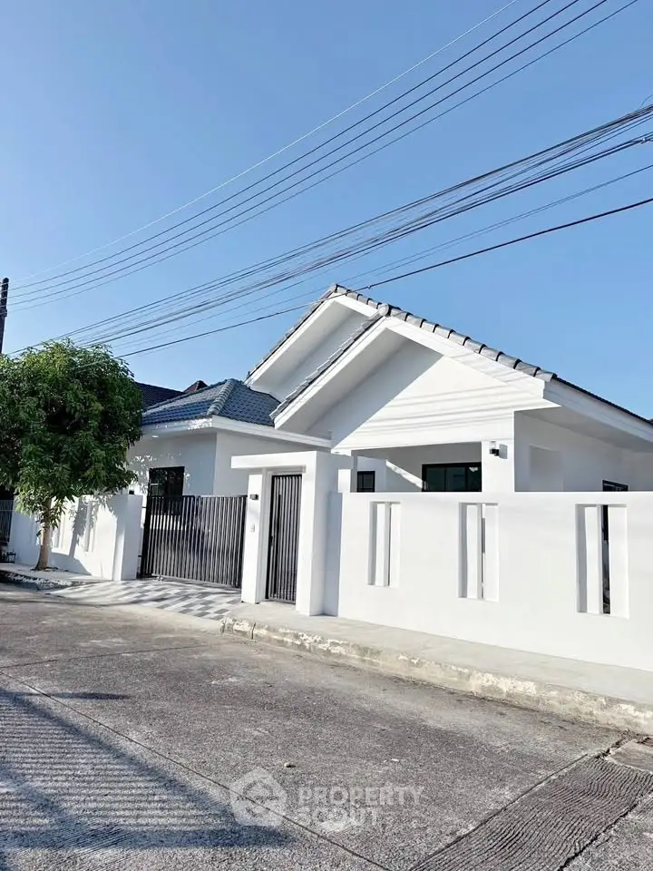Charming modern white house with sleek design and gated entrance in a serene neighborhood.