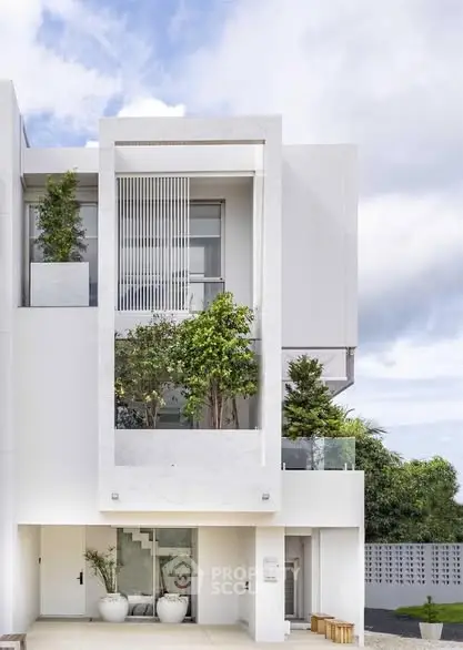 Modern white building exterior with lush greenery and sleek design.