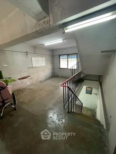Spacious industrial-style interior with concrete floors and stairway, ideal for creative workspace or studio.