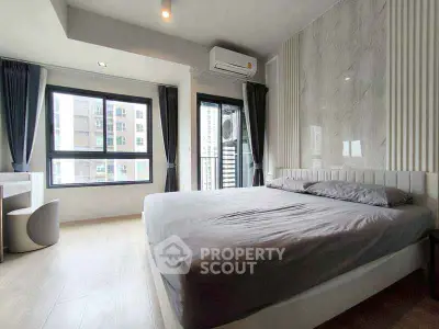 Modern bedroom with large windows and stylish decor in urban apartment.