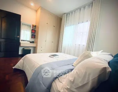 Cozy bedroom with elegant decor and natural light, featuring a comfortable bed and built-in wardrobe.