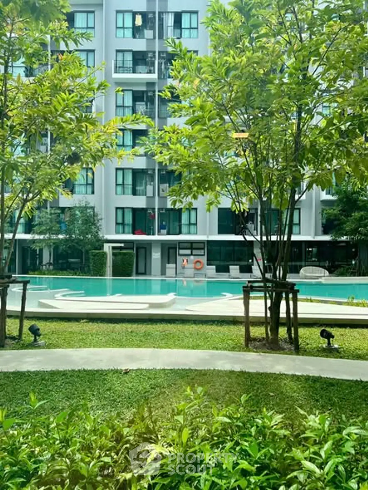 Modern apartment complex with lush garden and inviting swimming pool view.