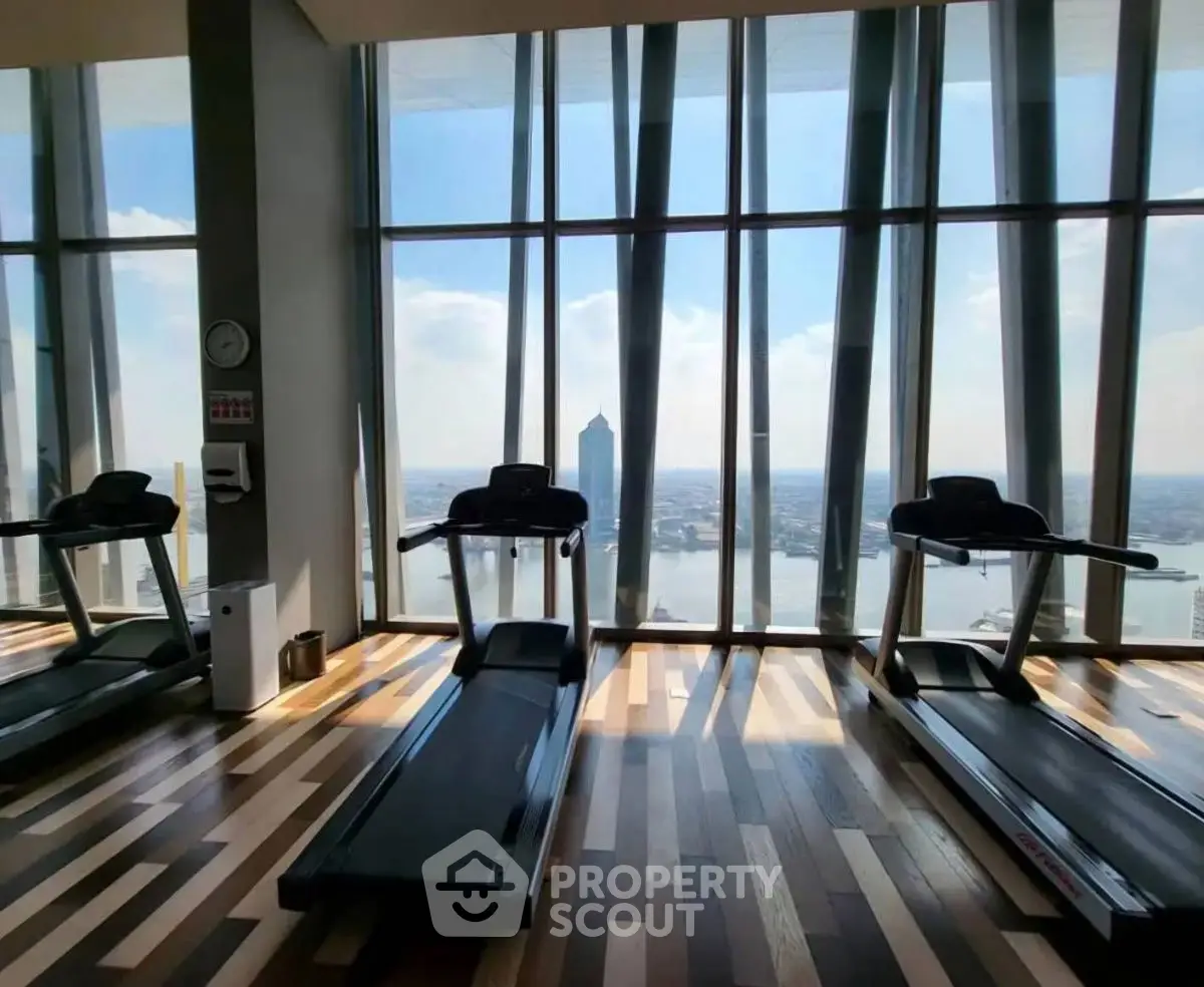 Luxurious gym with panoramic city view and modern treadmills in high-rise building.
