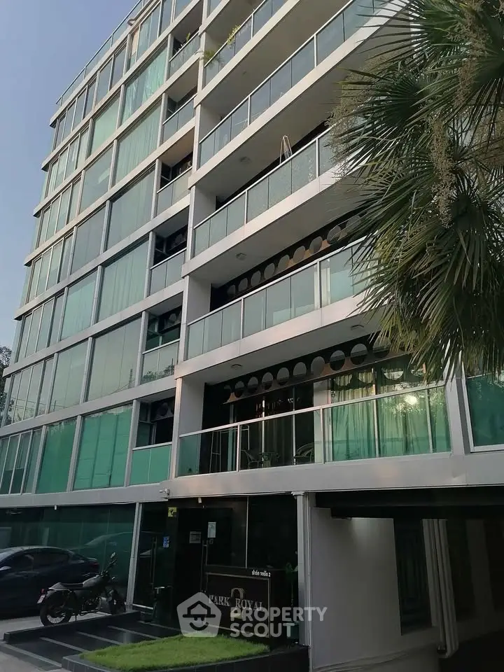 Modern multi-story building with glass balconies and lush greenery, ideal for urban living.