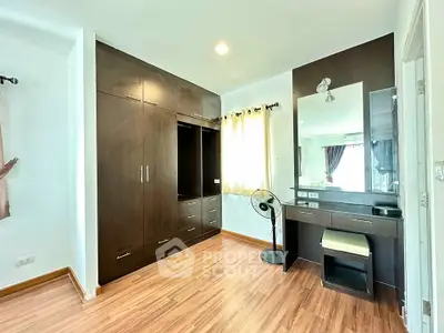 Spacious bedroom with elegant wooden wardrobe and vanity, featuring natural light and modern design.