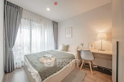 Cozy bedroom with modern decor and natural light, featuring a comfortable bed and stylish workspace.