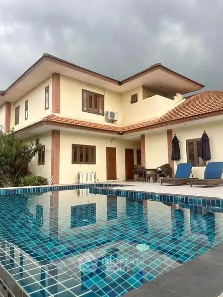 Luxurious villa with private pool and elegant architecture under a cloudy sky.