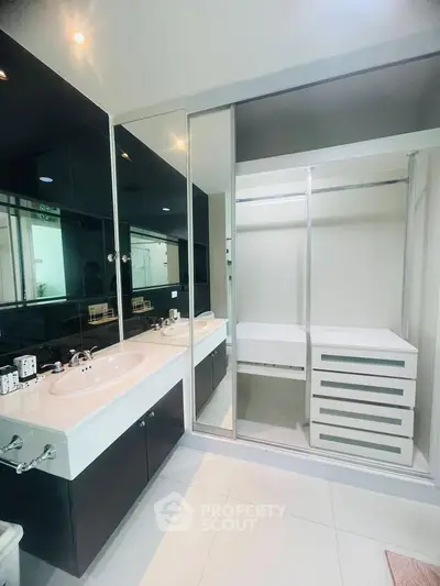 Modern bathroom with sleek black and white design, featuring dual sinks and spacious storage.