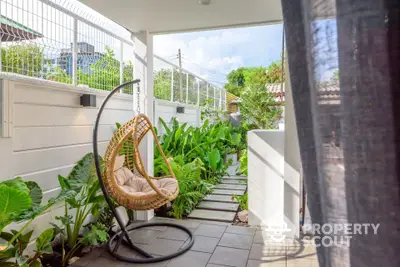 Charming garden patio with hanging chair and lush greenery