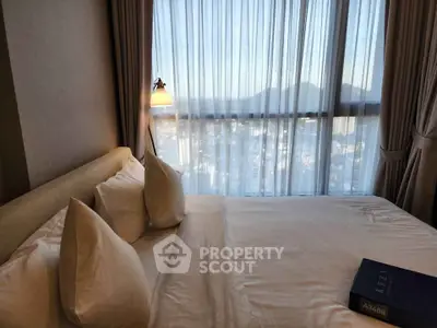 Luxurious bedroom with stunning city view through large windows, featuring elegant bedding and ambient lighting.