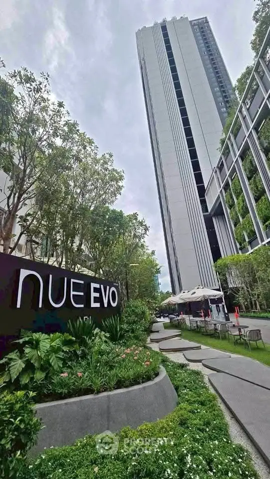 Modern high-rise building with lush landscaped gardens and outdoor seating area.