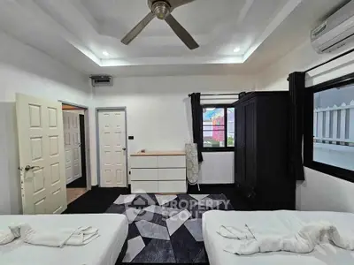 Spacious modern bedroom with twin beds, ceiling fan, and ample storage in a stylish home.