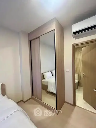 Modern bedroom with mirrored wardrobe and ensuite bathroom in a stylish apartment.
