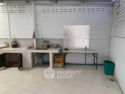 Spacious kitchen with tiled floor and open layout, featuring a sink and ample counter space.
