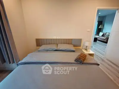 Cozy bedroom with modern decor and view into spacious living area.