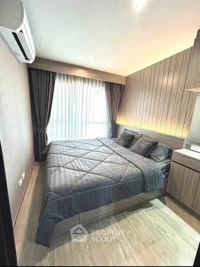 Modern bedroom with stylish wood paneling and cozy bedding in a well-lit apartment.
