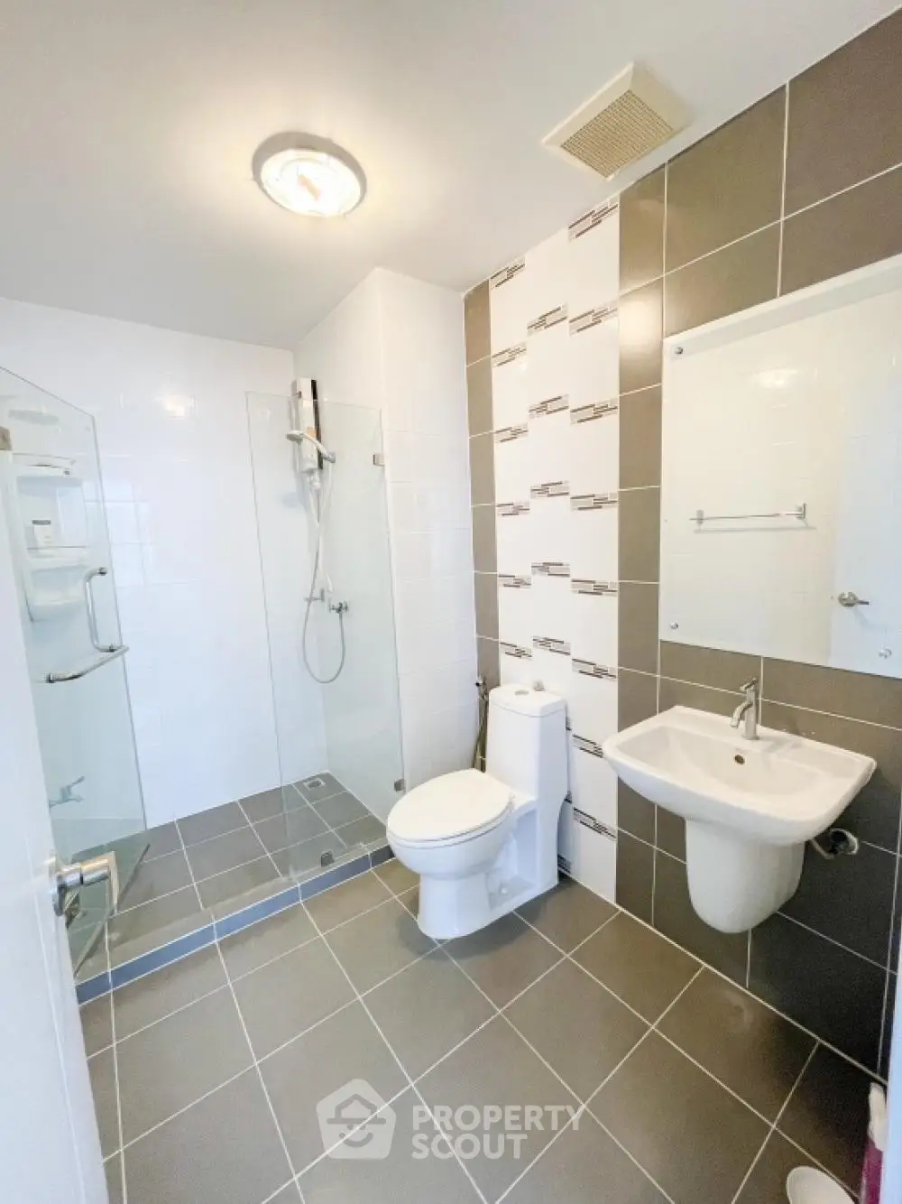 Pristine modern bathroom with walk-in shower, sleek tiling, and essential fixtures, perfect for a refreshing start to the day.