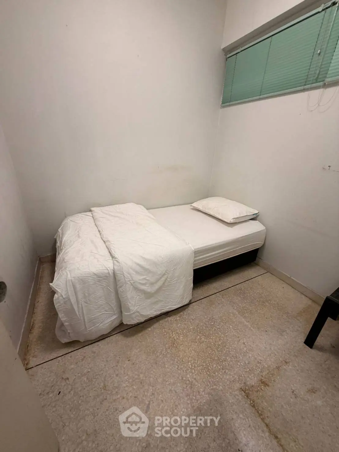 Cozy minimalist bedroom with single bed and simple decor, ideal for compact living spaces.
