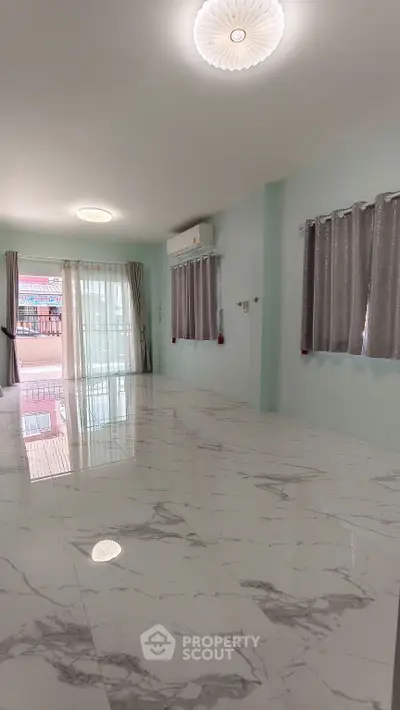 Spacious modern living room with marble flooring and large windows for natural light.