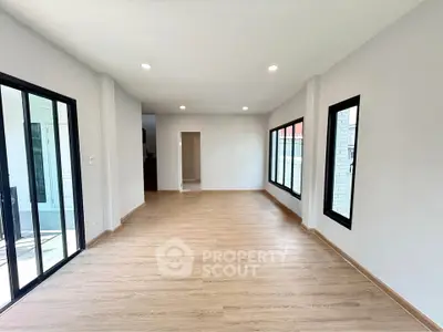 Spacious modern living room with large windows and wooden flooring
