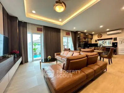 Luxurious open-plan living room with leather sofa and modern kitchen, perfect for entertaining.