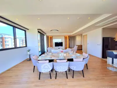 Spacious modern living room with dining area and large windows offering natural light.